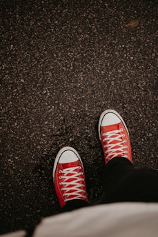 a person wearing red sneakers standing on a sidewalk