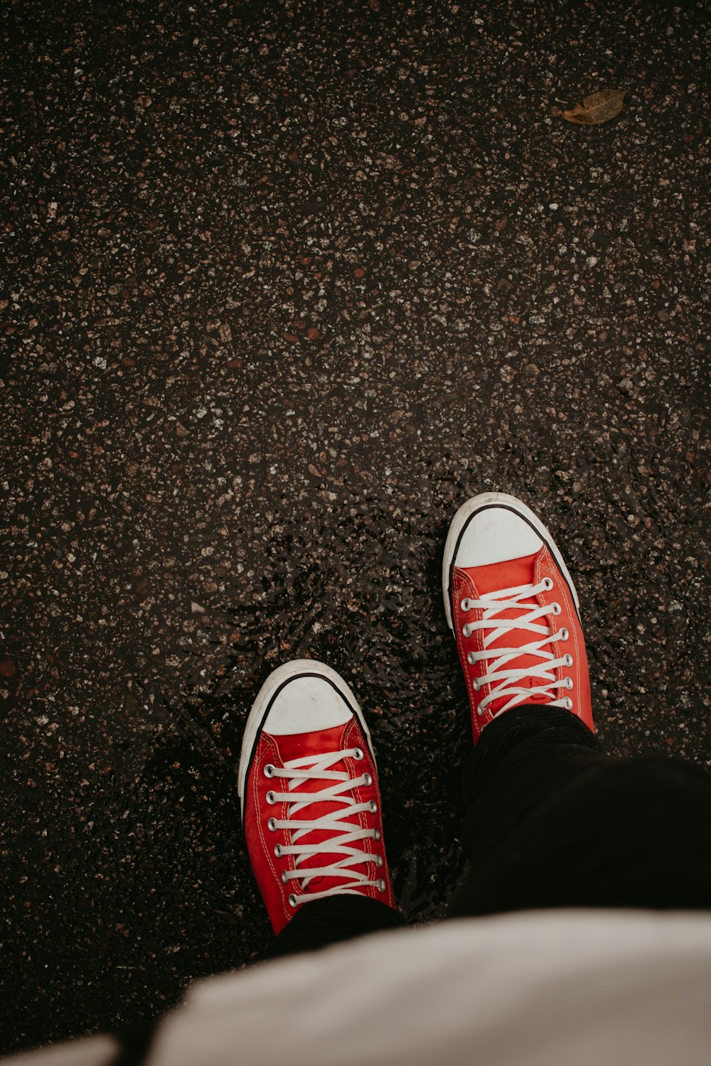 a person wearing red sneakers standing on a sidewalk