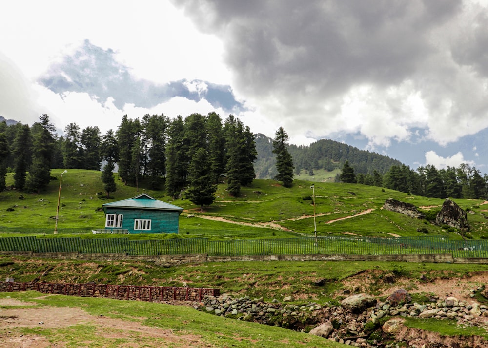 a small blue house on a green hillside