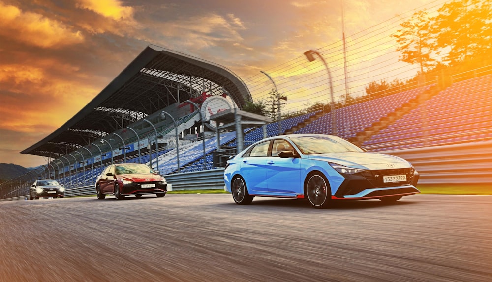 two cars driving down a race track in front of a stadium