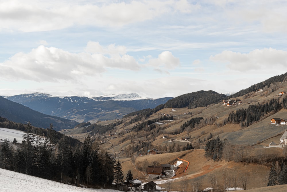 a snow covered hillside with houses and mountains in the background