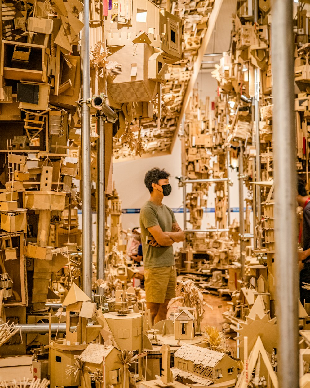 a man standing in front of a pile of wooden buildings