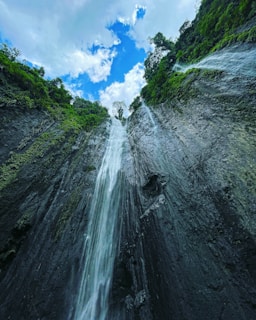 a very tall waterfall in the middle of a forest