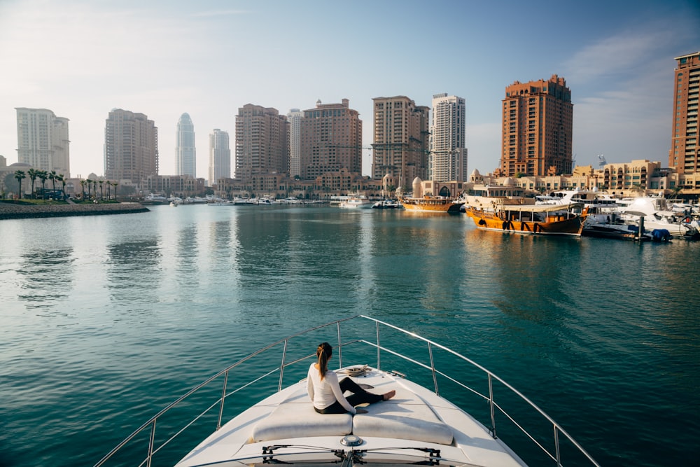 a man sitting on the bow of a boat in a harbor