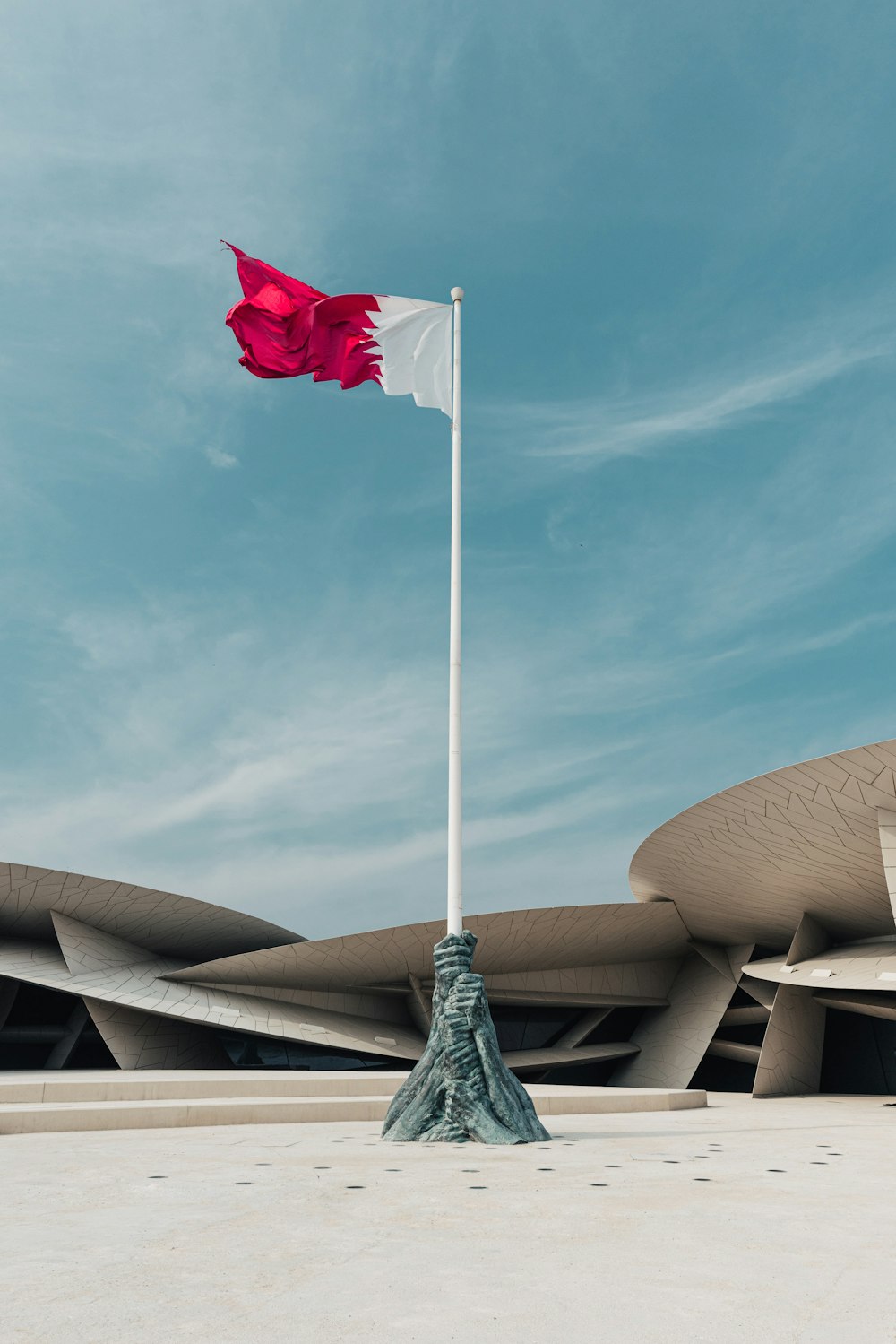a red and white flag on a pole in front of a building