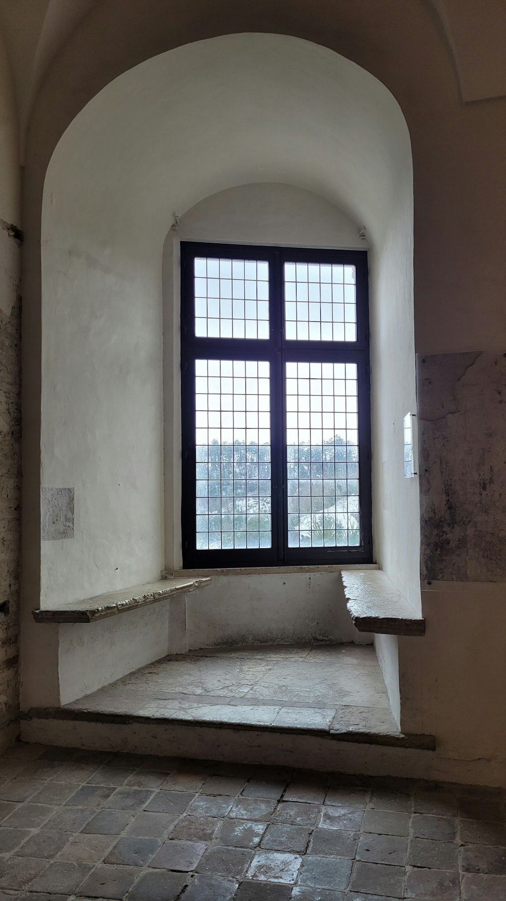 an empty room with a window and a stone floor