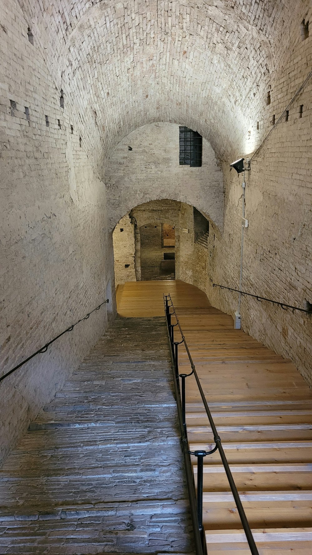 a wooden staircase leading up to a brick tunnel