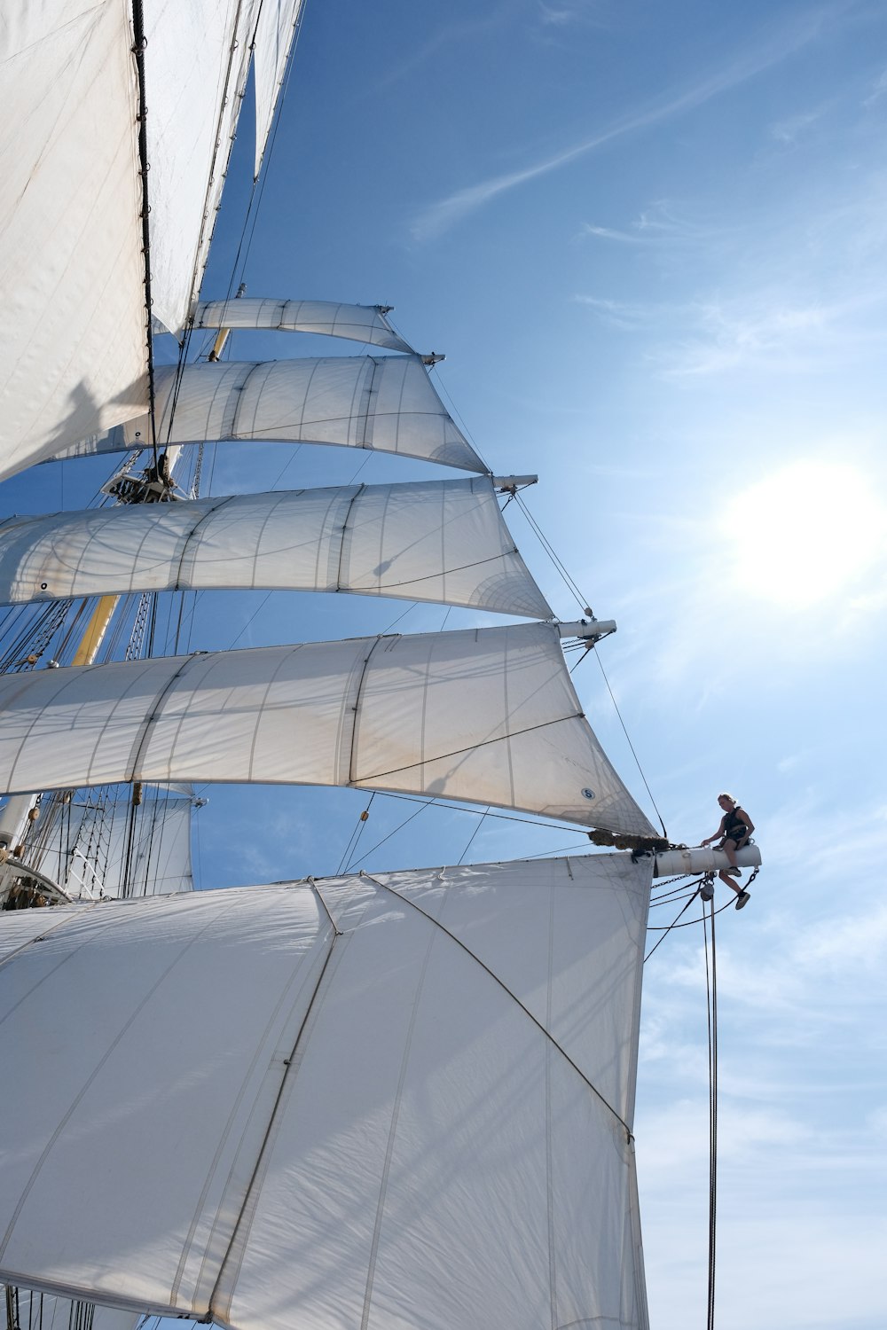 a sailboat with white sails on a sunny day