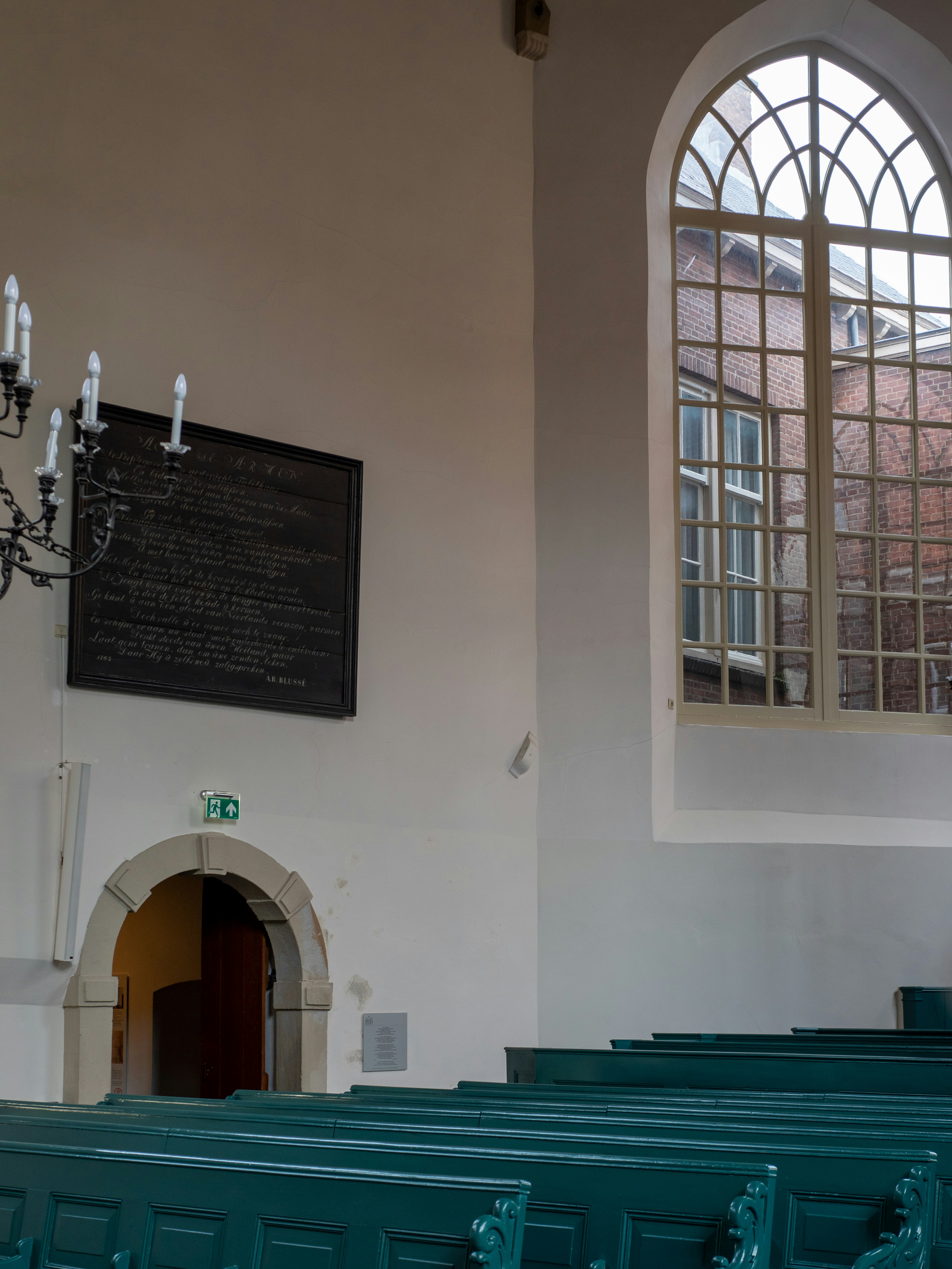 a church with rows of green pews and a chandelier