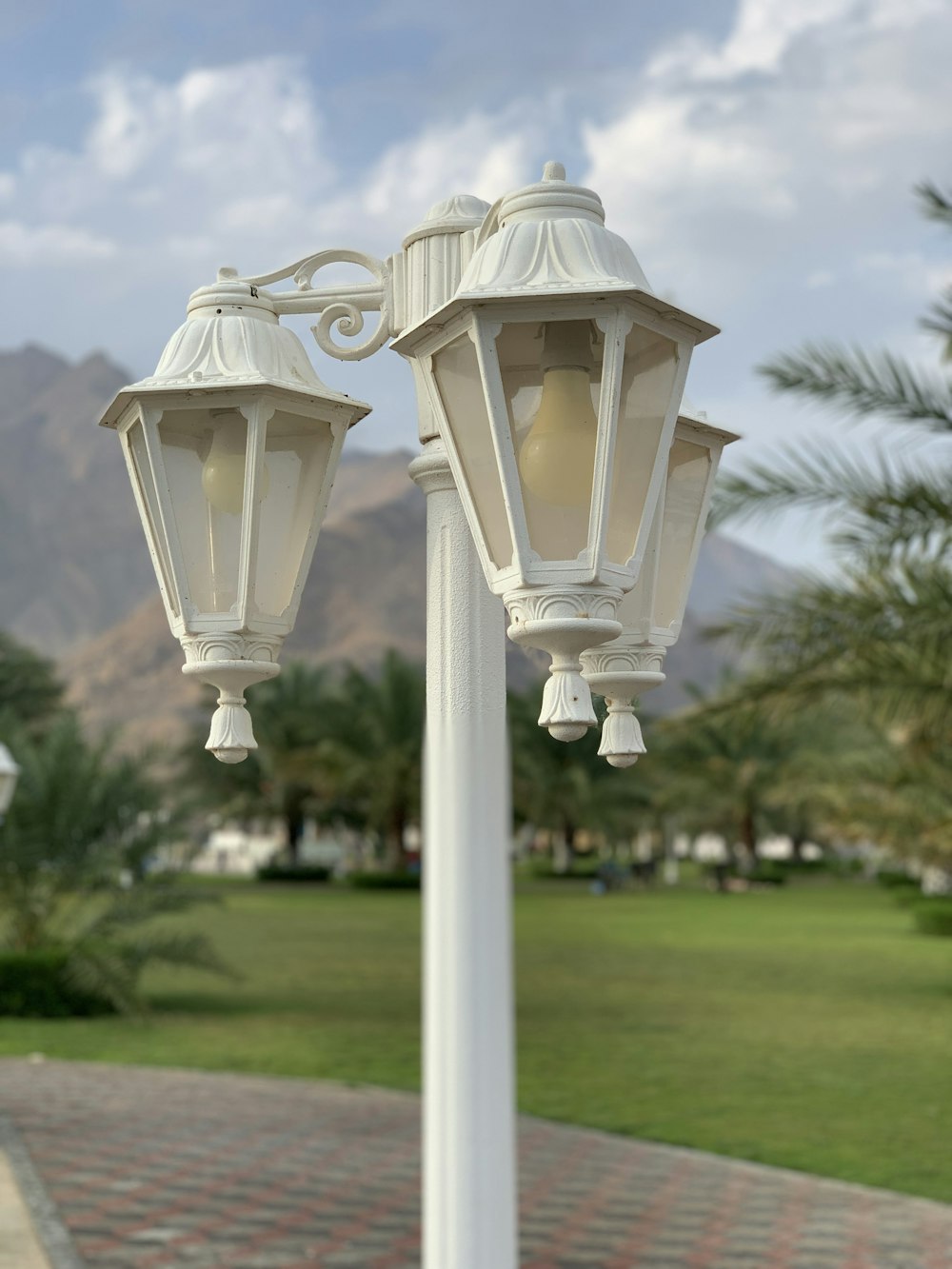 a couple of white street lights sitting on top of a white pole