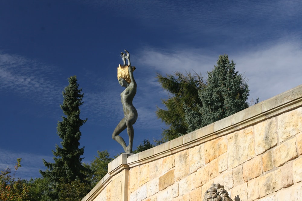 a statue of a woman holding a banana on top of a stone wall