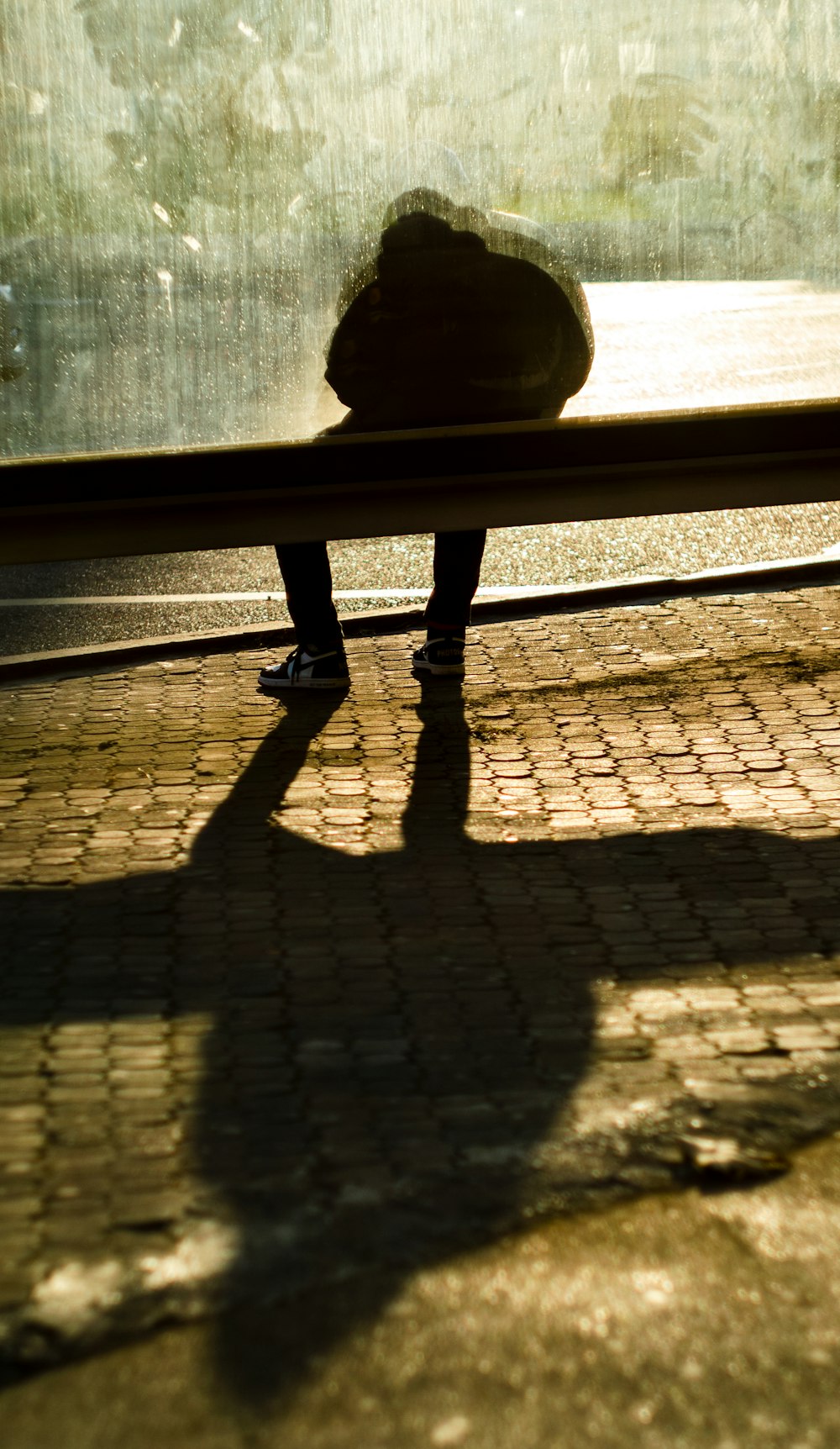a shadow of a person sitting on a bench