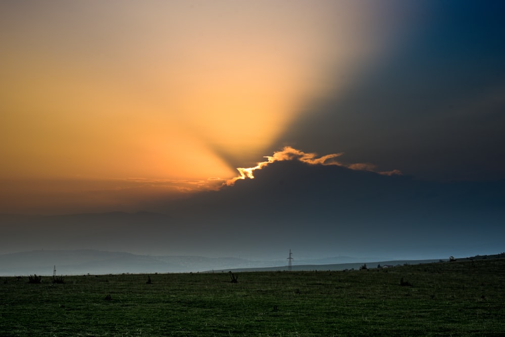 the sun is setting over a grassy field