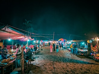 a group of people standing around a market at night