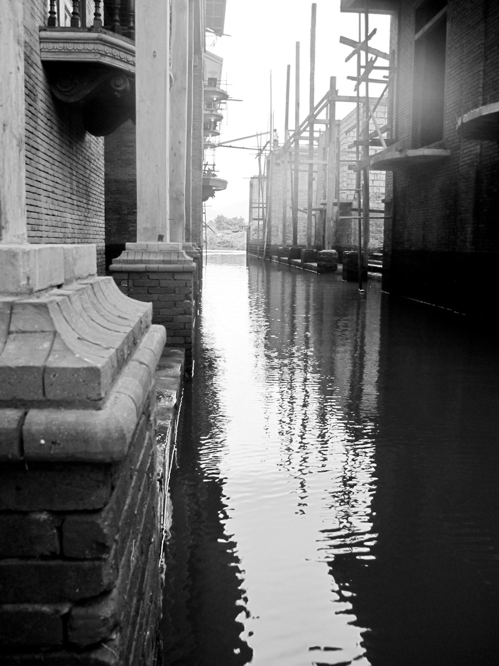 a black and white photo of a canal in a city