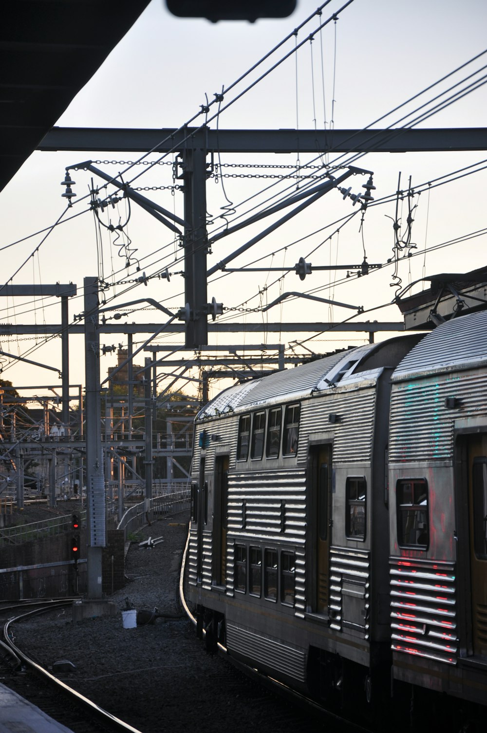 a silver train traveling down train tracks next to a train station