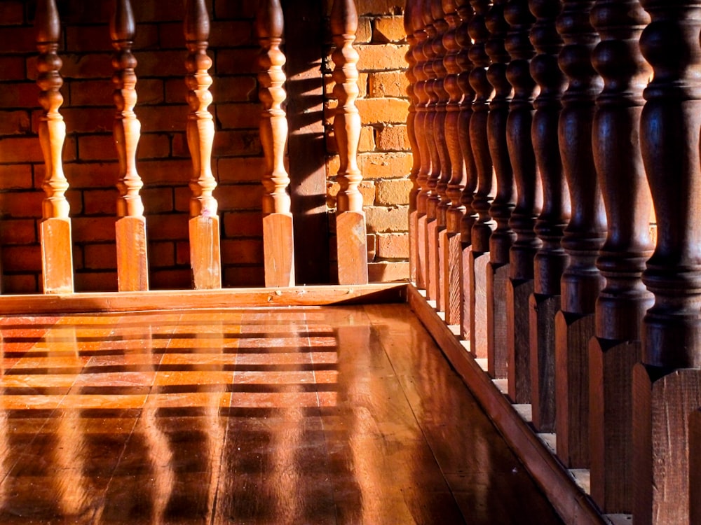 a close up of a wooden railing with a brick wall in the background