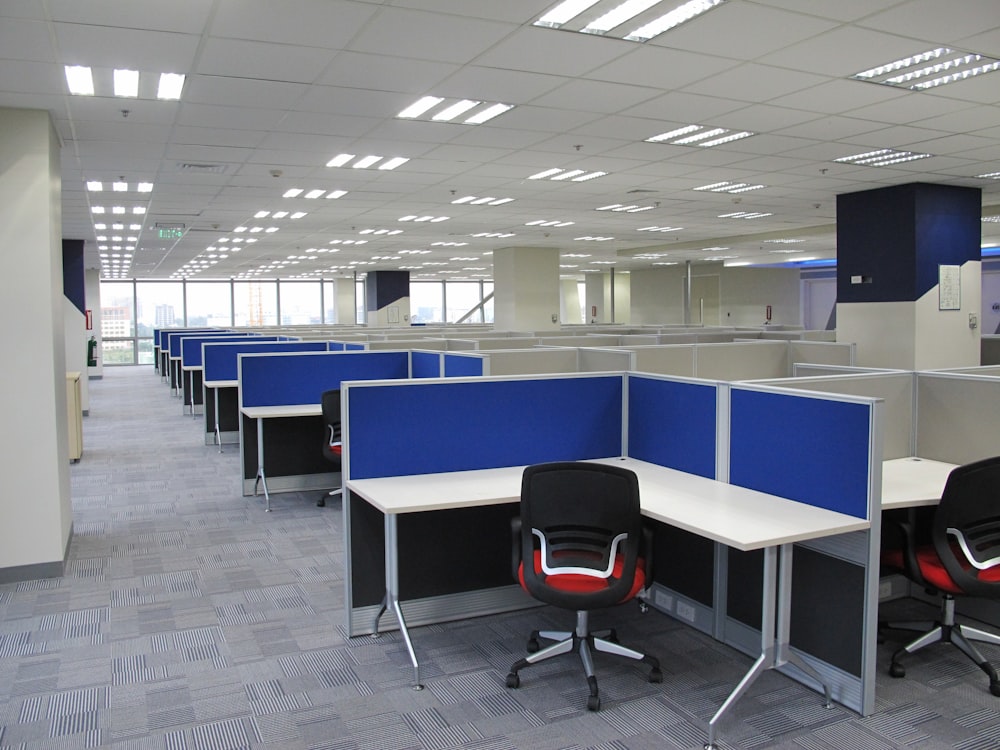 an empty office cubicle with chairs and desks
