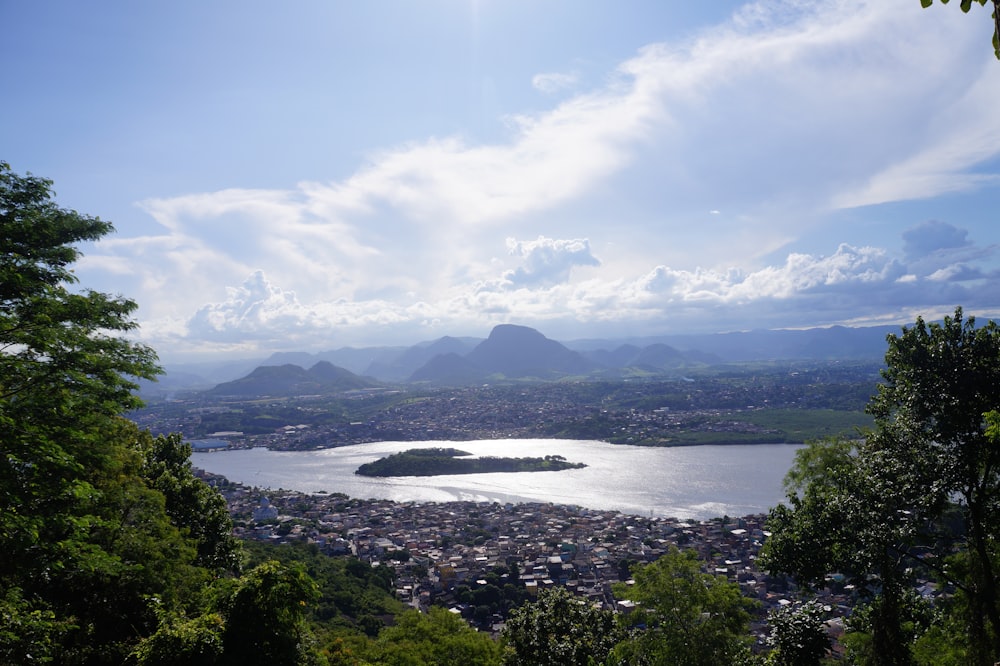 a lake surrounded by trees and mountains under a blue sky