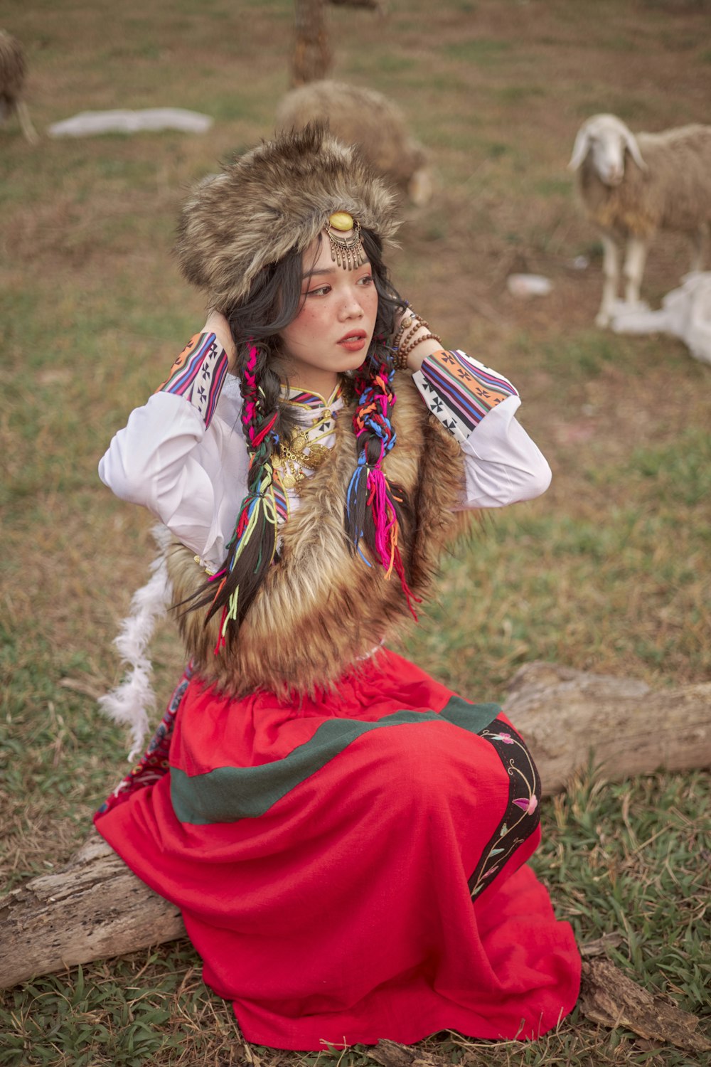 a woman sitting on a log wearing a fur hat