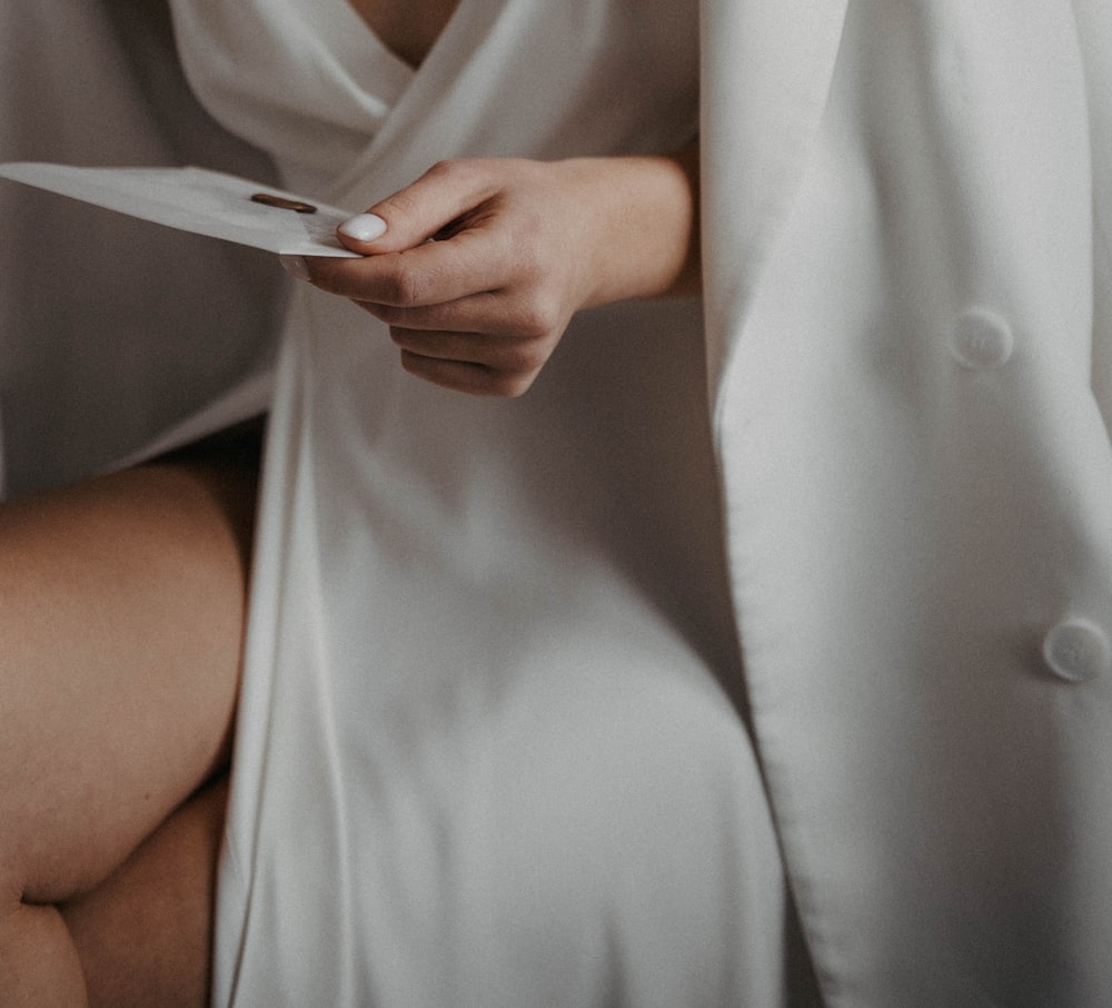 a woman in a white dress holding a piece of paper