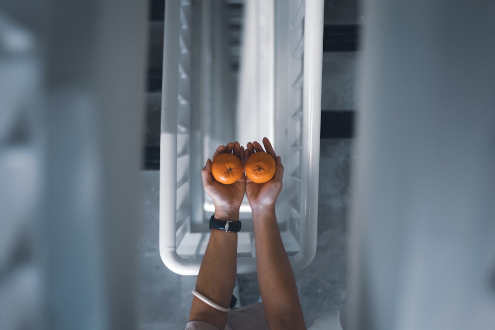 a person holding two oranges in their hands