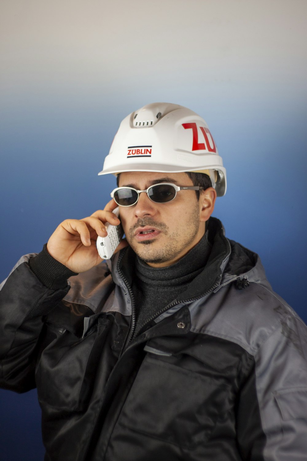 a man in a hard hat talking on a cell phone