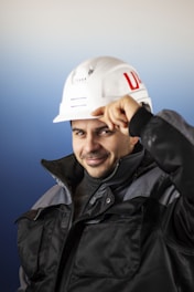 a man wearing a white hard hat and black jacket