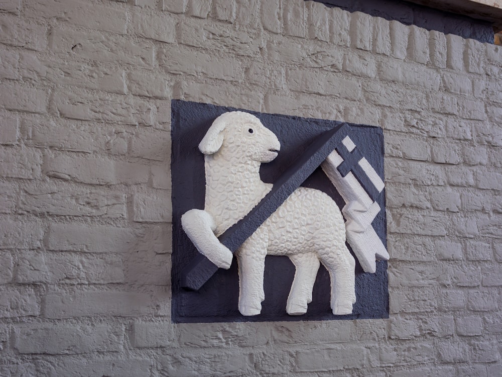 a sculpture of a sheep holding a sword on a brick wall