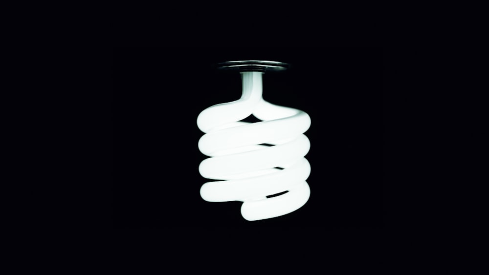 a white light bulb hanging from a black ceiling