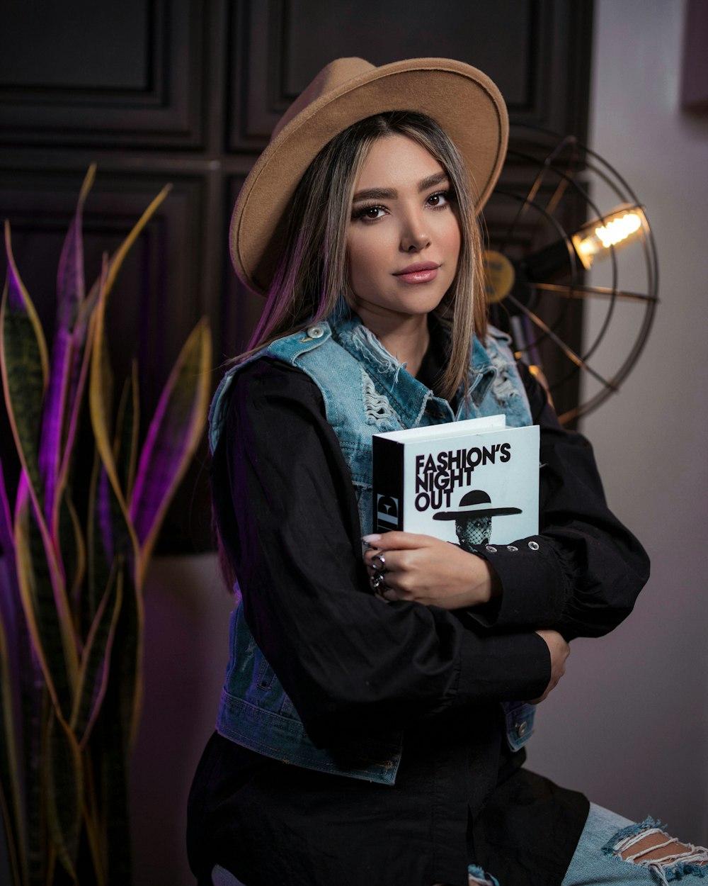 a woman in a hat is holding a book