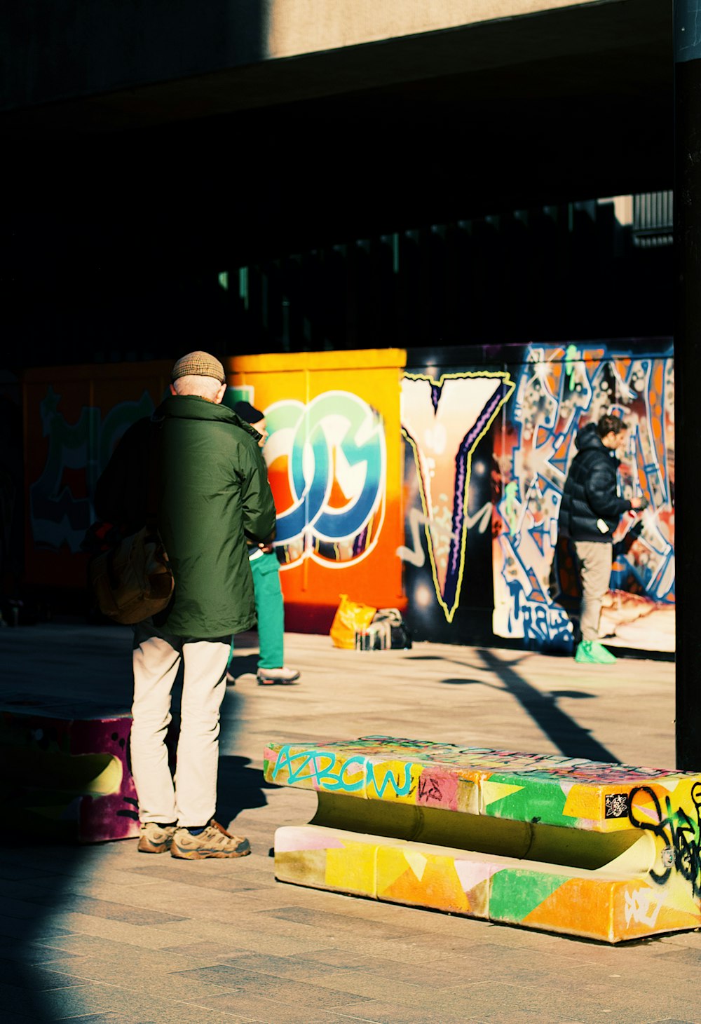 a man standing next to a pole with graffiti on it