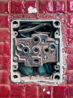 Electrician repairing a wall socket with safety gloves on.
