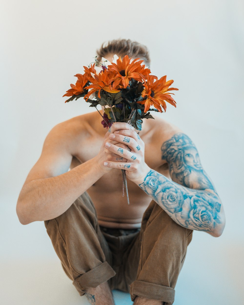 a man sitting on the ground holding a bunch of flowers