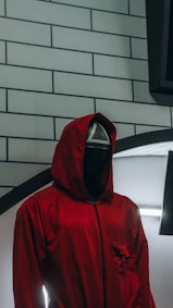 a person in a red jacket standing in front of a brick wall