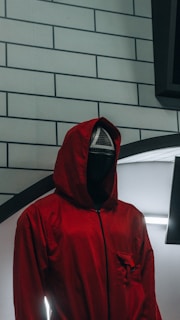 a person in a red jacket standing in front of a brick wall