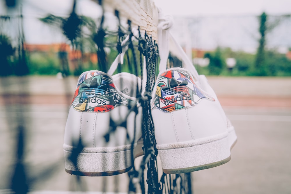 a pair of white tennis shoes hanging on a fence