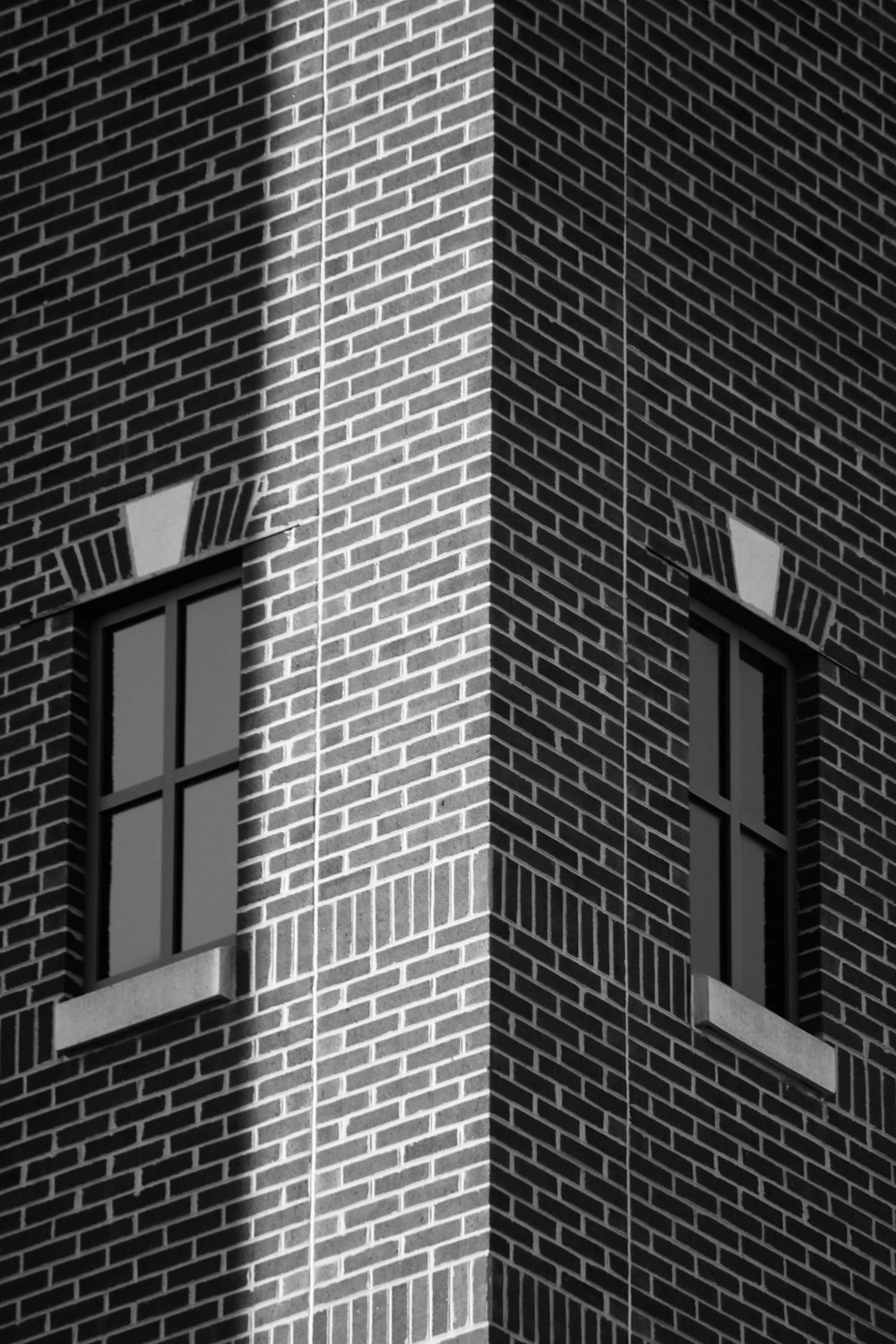 a black and white photo of two windows on a brick building