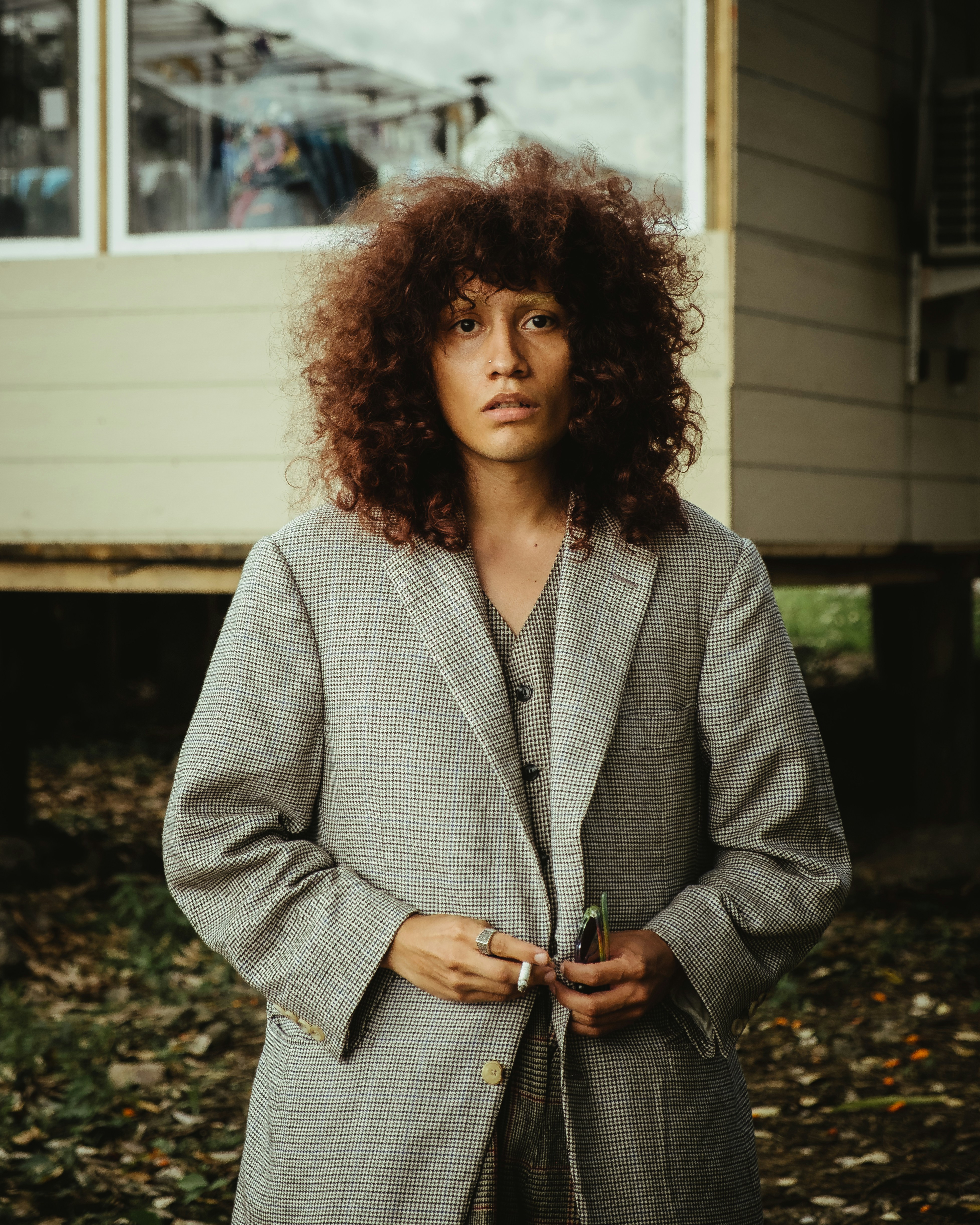 a woman with curly hair standing in front of a house