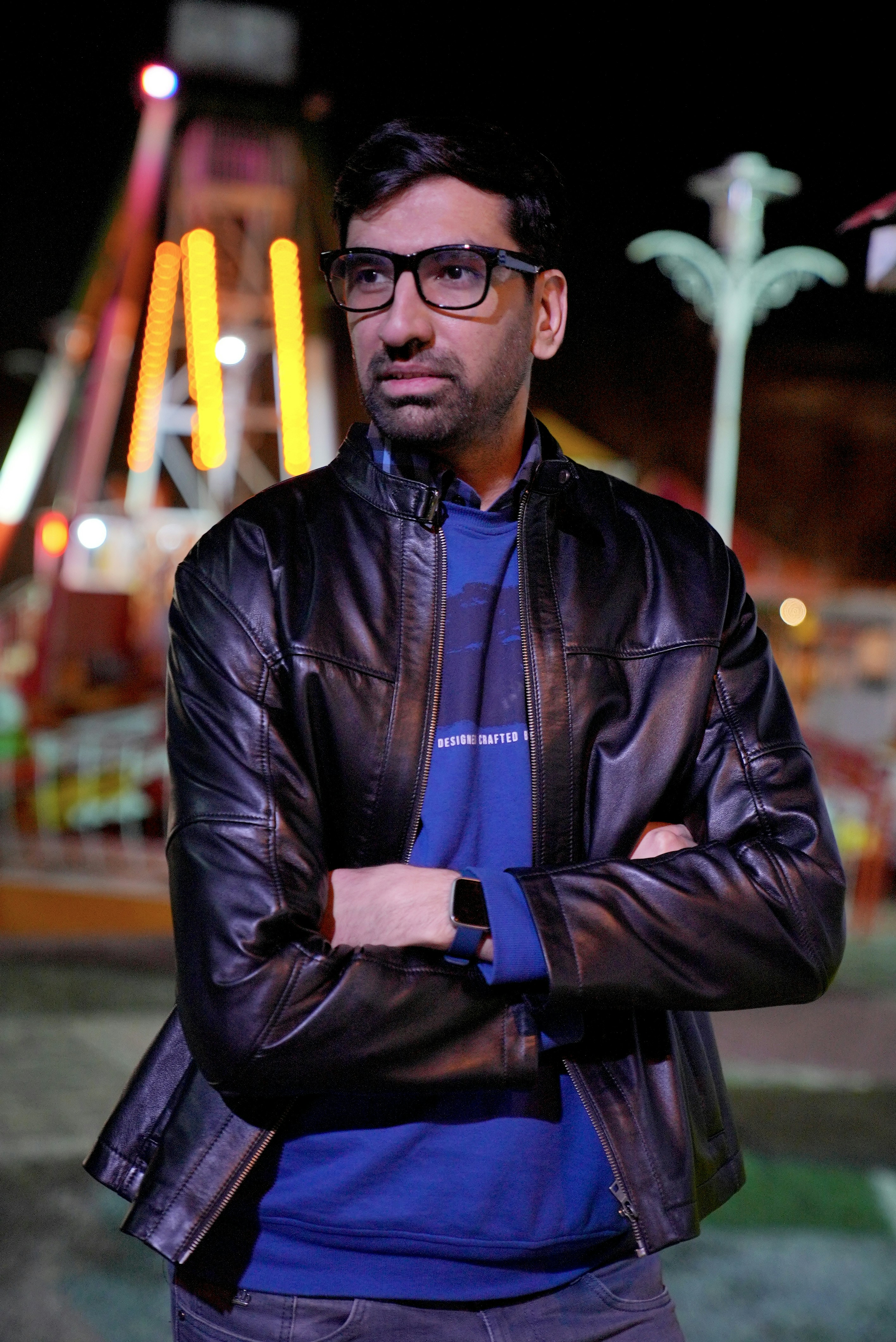 A man wearing glasses standing in front of a roller coaster photo Free Apparel Image on Unsplash
