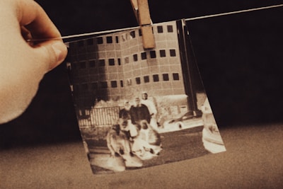 a hand holding a photo of two men and a dog