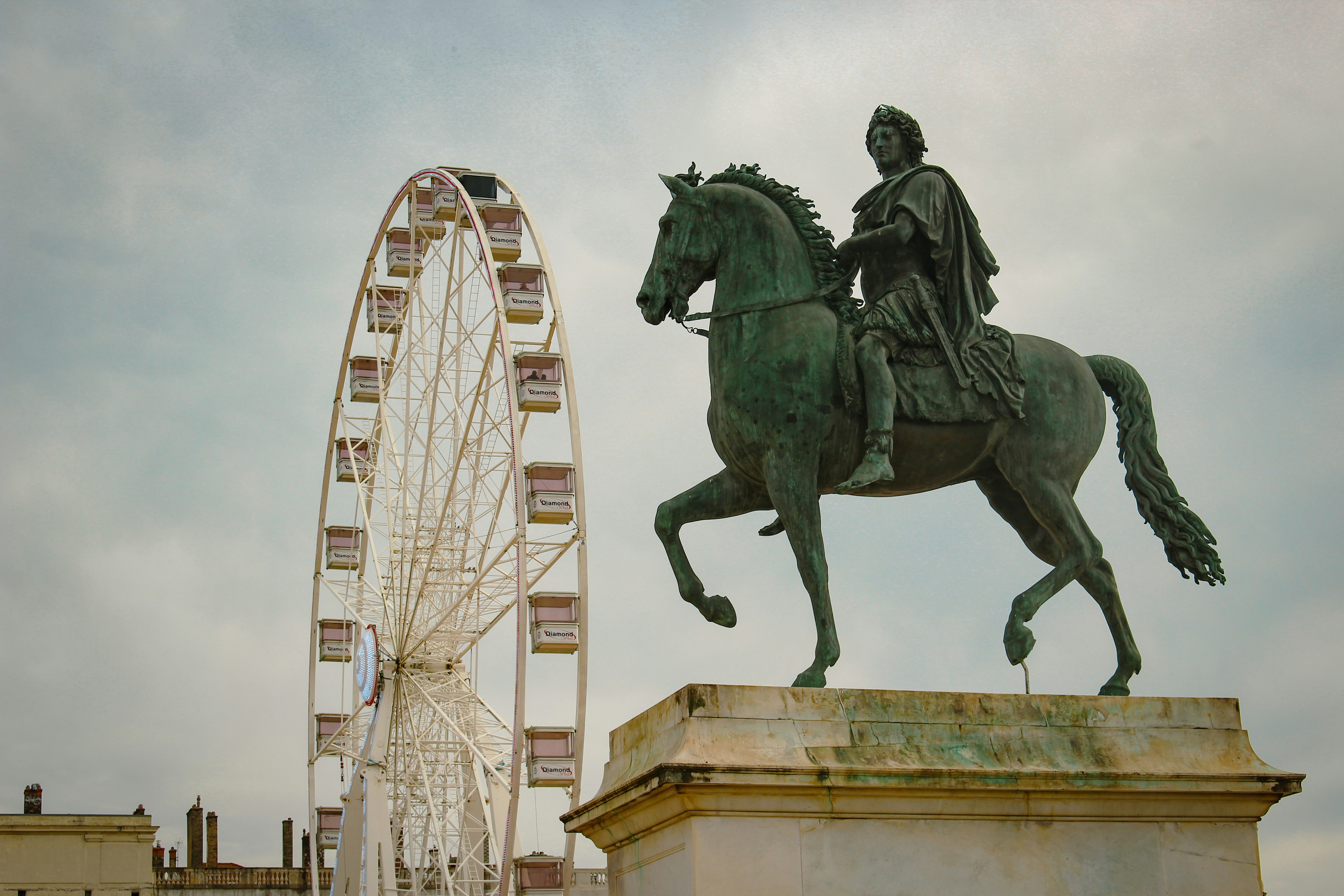 a statue of a man riding a horse next to a ferris wheel
