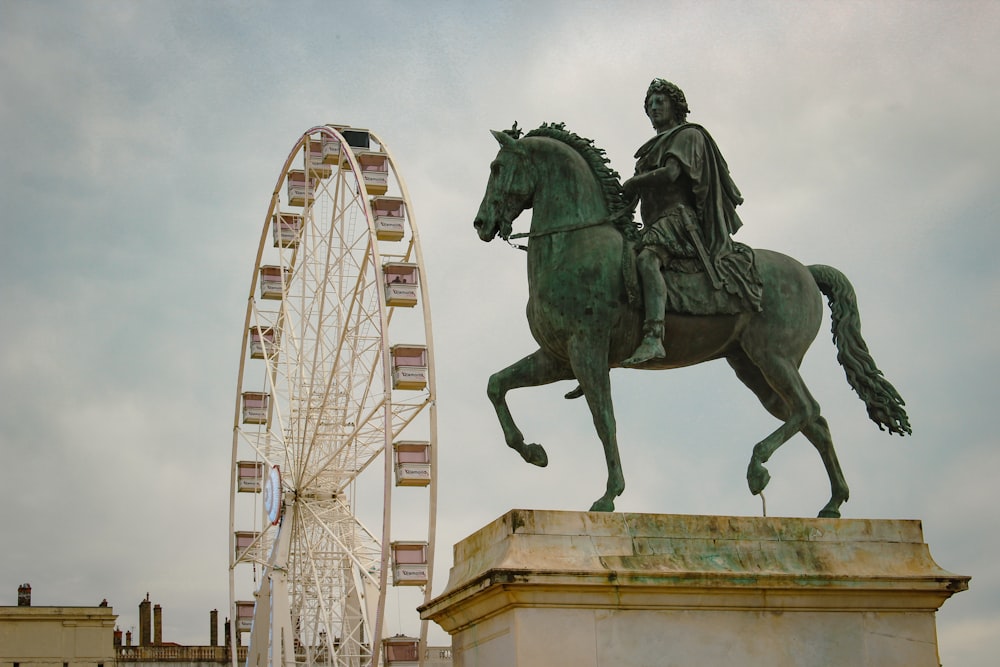 Une statue d’un homme à cheval à côté d’une grande roue
