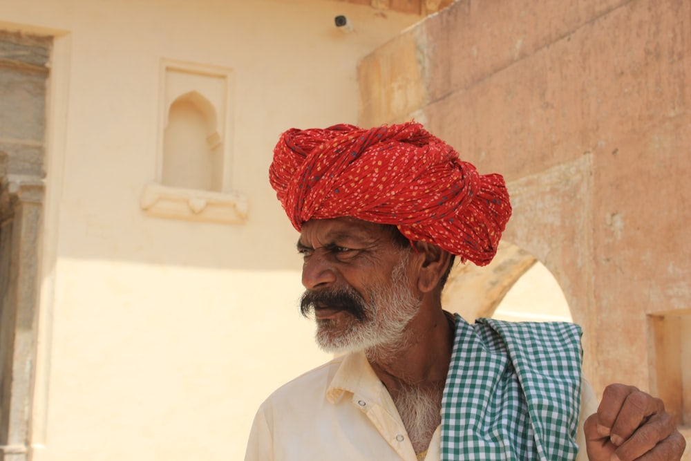 Un homme avec un turban rouge debout devant un immeuble