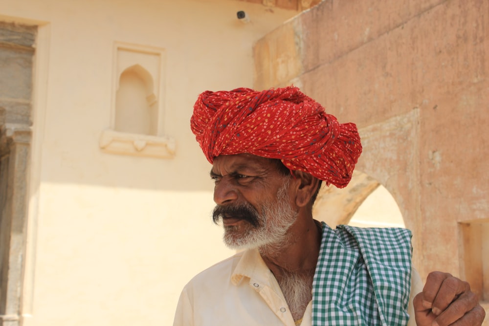 a man with a red turban standing in front of a building