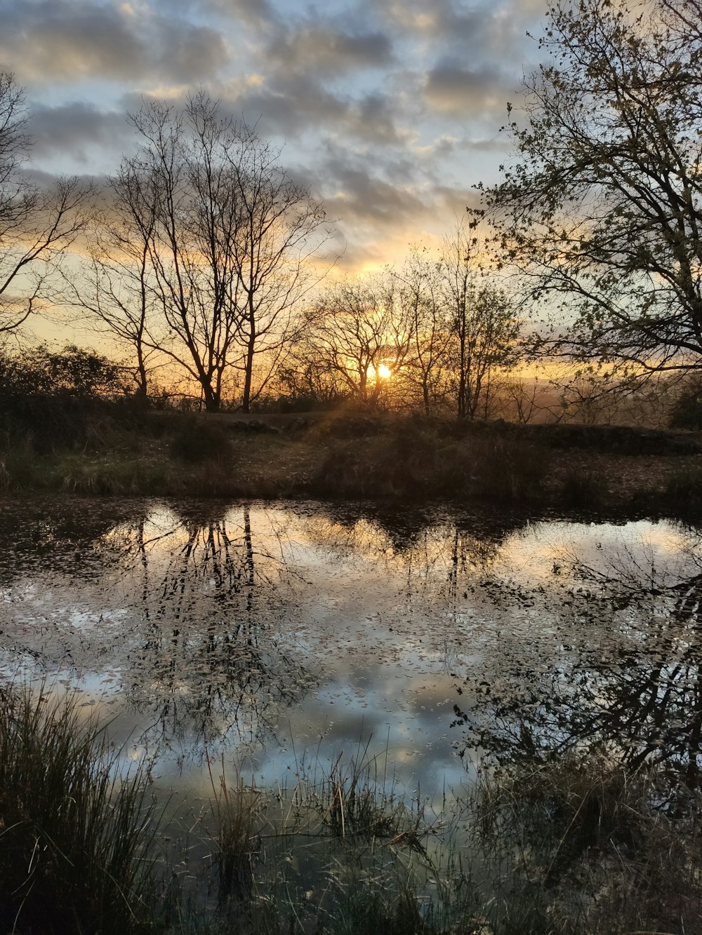 the sun is setting over a small lake