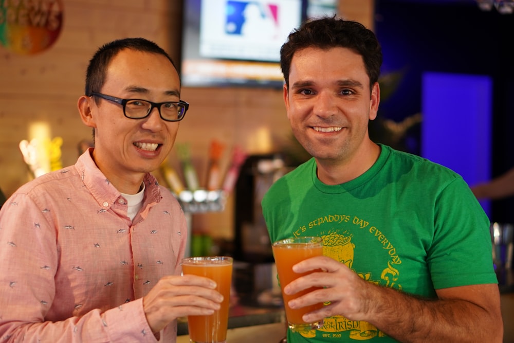 a couple of men sitting next to each other holding drinks