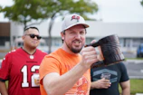 A smiling member holding their personalized Mug Club mug outdoors.