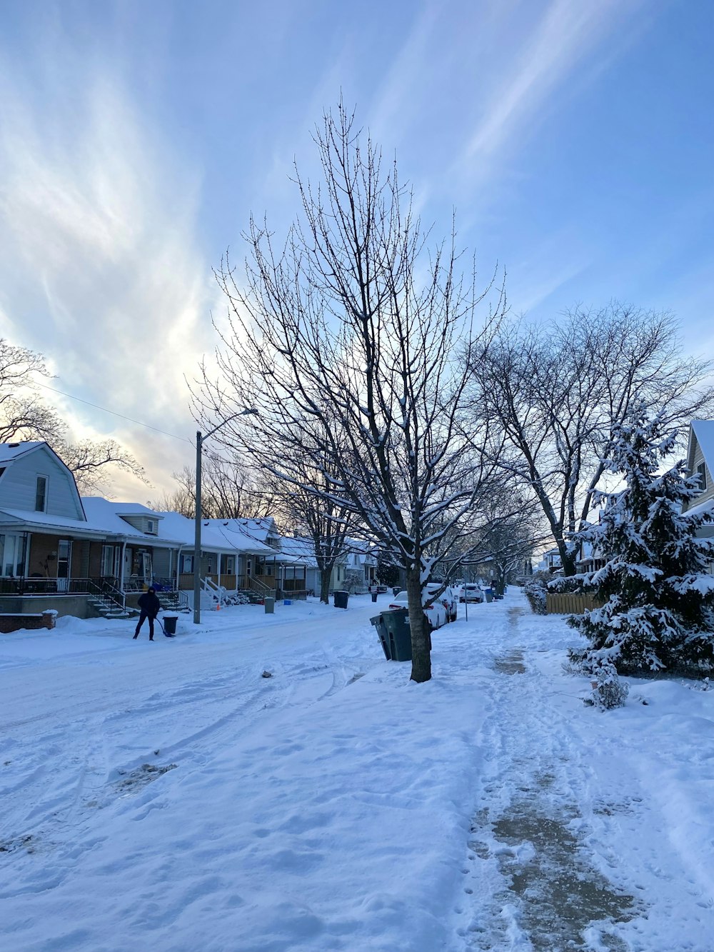 a snow covered street with houses and trees