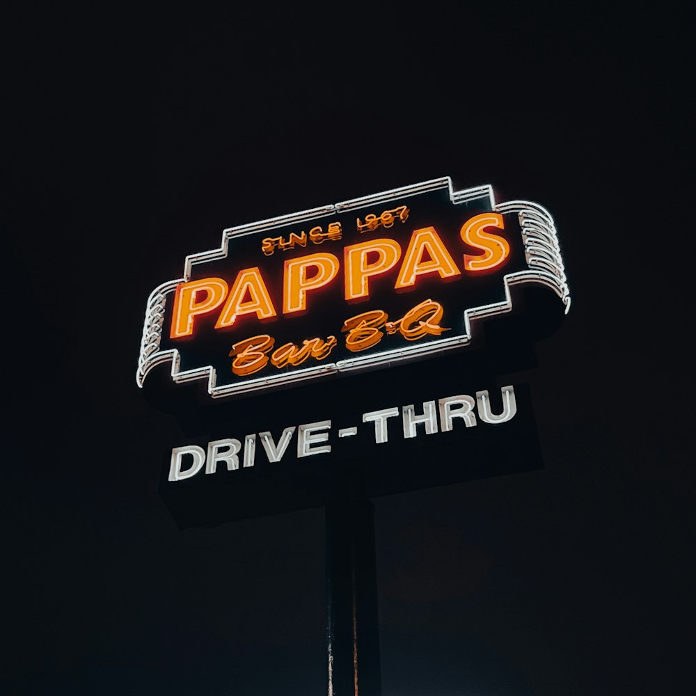 a neon sign for papa's drive thru in the dark